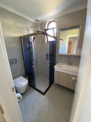 a bathroom with a shower and a toilet and a sink at The Diplomat Hotel in Turunç