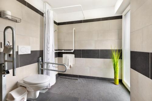 a bathroom with a toilet and a plant at Nyíltvízi Edzőközpont in Dunakeszi