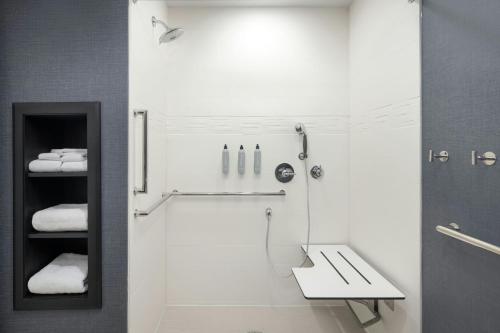 a white bathroom with a shower and a sink at Residence Inn by Marriott Battle Creek in Battle Creek