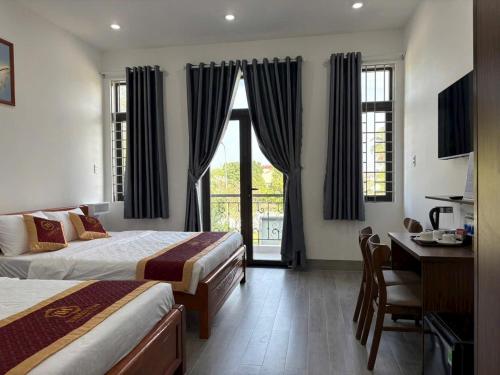 a bedroom with two beds and a desk and a window at THIÊN HÀ Motel in Soc Trang