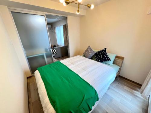 a bedroom with a bed with a green blanket on it at ホロムア澄川 in Sapporo