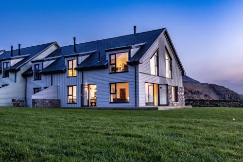 a large white house on a grass field at Porthdinllaen by Together Travel - Luxury 5-Bed Holiday Retreat in Pistyll