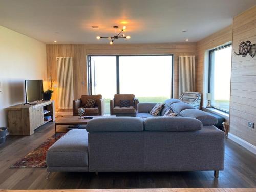 a living room with a couch and a tv at Porthdinllaen by Together Travel - Luxury 5-Bed Holiday Retreat in Pistyll