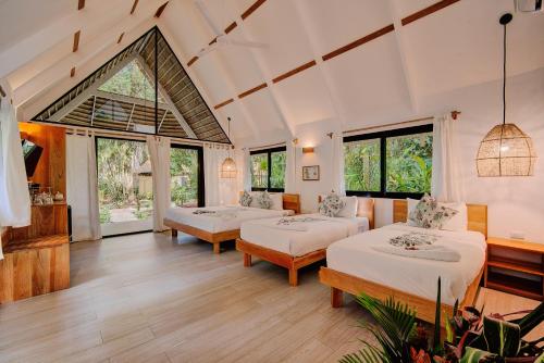 a room with three beds and windows at Hotel Shawandha Costa Rica in Puerto Viejo