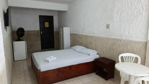 a small bedroom with a bed and a small table at HOTEL LIVRAMENTO Maceió in Maceió