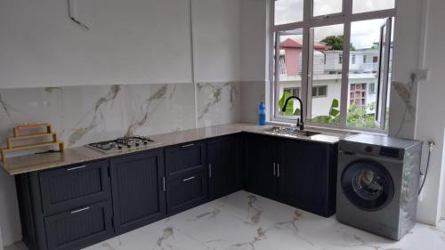 a kitchen with a sink and a washing machine at kooshal Seetul Flacq Flat in Centre de Flacq