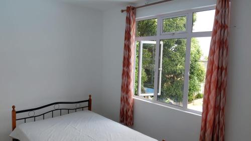 a bedroom with a bed and a window at kooshal Seetul Flacq Flat in Centre de Flacq