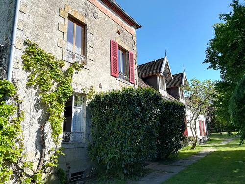a building with red windows and a hedge at Chambres d'hôtes de Champendu in Azy-le-Vif