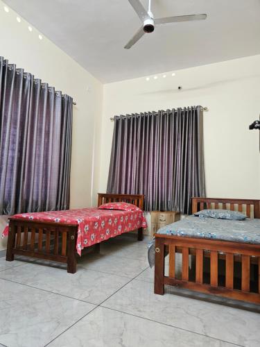 a bedroom with two beds and a ceiling fan at Rajadhani Apartment in Karunāgapalli
