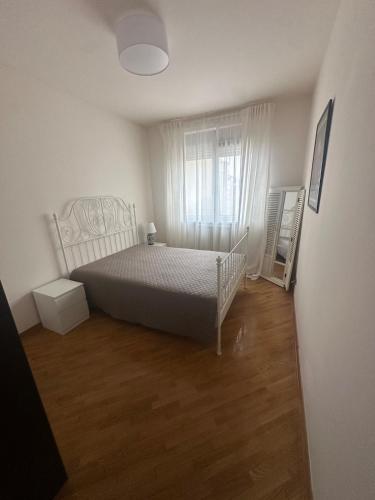 a white bedroom with a bed and a window at Ada Corner in Belgrade