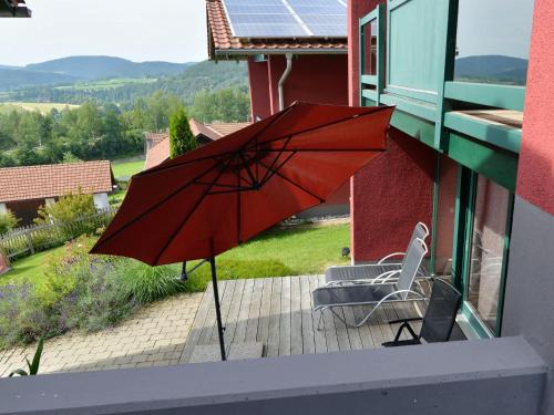 a red umbrella sitting on a patio with a chair at Rosy Holiday Home in Blossersberg with Private Terrace in Viechtach