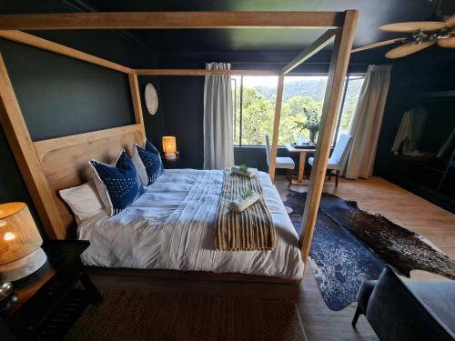 a bedroom with a canopy bed with blue pillows at Forest Nature Spa in Plettenberg Bay