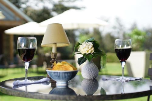 two glasses of red wine and a bowl of fruit on a table at La Palma Polo Hotel - Airport Area in Puembo