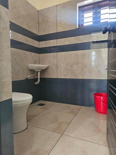 a bathroom with a toilet and a sink at Rajadhani Apartment in Karunāgapalli