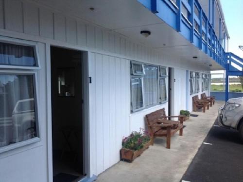 a building with a door and benches on a sidewalk at Dargaville Motel in Dargaville
