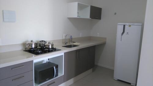 a kitchen with a sink and a refrigerator at Loft Florianópolis no Campeche in Florianópolis