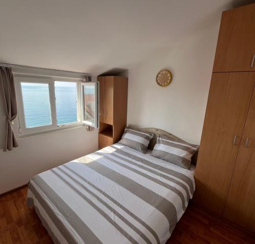 a bedroom with a large bed and a window at Apartments Teodora Obala in Petrovac na Moru