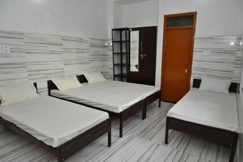 three beds in a room with a wall at Sarvjanik Hindu Dharamshala in Nīmri