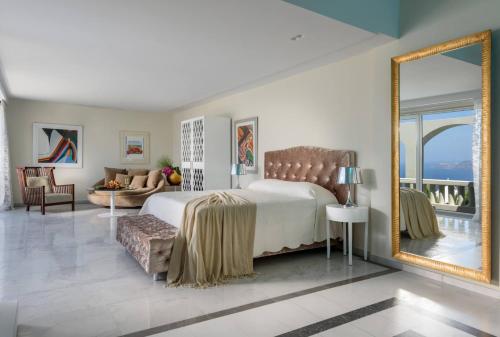 a bedroom with a large bed and a mirror at Santorini Gem in Órmos Athiniós