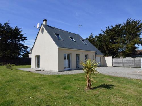 a white house with a black roof in a yard at Seafront holiday home with garden in Denneville in Denneville