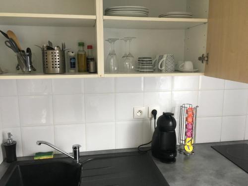 a kitchen with a sink and white tiled walls at Appart&Spa in Toulouse