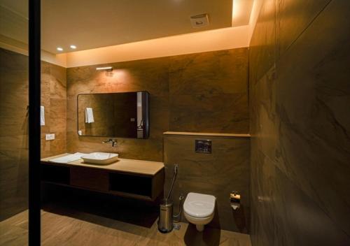 a bathroom with a toilet and a sink and a mirror at Vanasya Retreat Corbett in Amgarhi