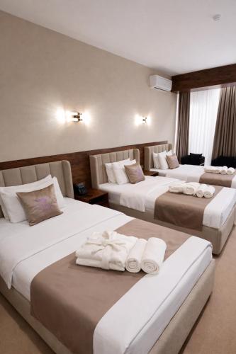 a hotel room with three beds with towels on them at GRAND CARAVAN in Tashkent