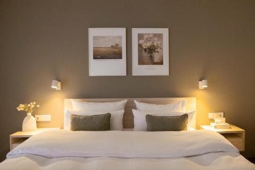 a bedroom with a large white bed with three pictures on the wall at The Resting Place in Lemgo