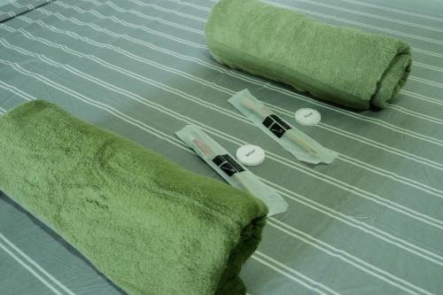 a bed with green sheets and two pillows on it at Tukad Guest House in Sampong