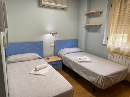 two beds in a hospital room with towels on them at REMANAL Residencia in Salamanca