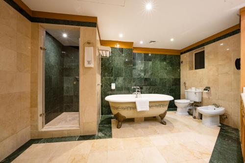 a bathroom with a tub and a toilet and a sink at Luxe Avenue Hotel in Dubai