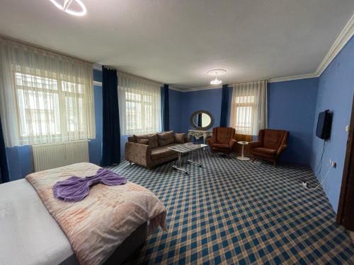 a bedroom with blue walls and a bed and a couch at Kutlu suit otel in Eskiömerler