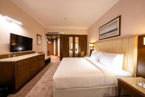 a bedroom with a large bed and a flat screen tv at Luxe Avenue Hotel in Dubai