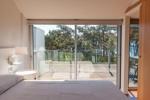 a bedroom with a bed and a large glass window at Santi Cabodeiro in Isla de Arosa