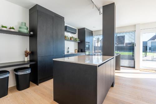a kitchen with black cabinets and a large island at Luxury Apartment with 4 Rooms, Pool and Modern Comfort in De Haan