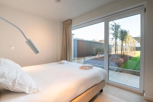 a bedroom with a bed and a large window at Luxury Apartment with 4 Rooms, Pool and Modern Comfort in De Haan