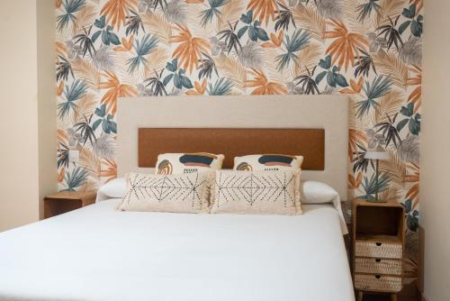 a bedroom with a white bed with a floral wallpaper at Apartamentos GO - Simancas in Simancas