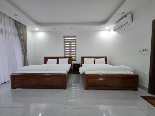 two beds in a room with white walls at Tam Coc Natura Hotel in Văn Lâm