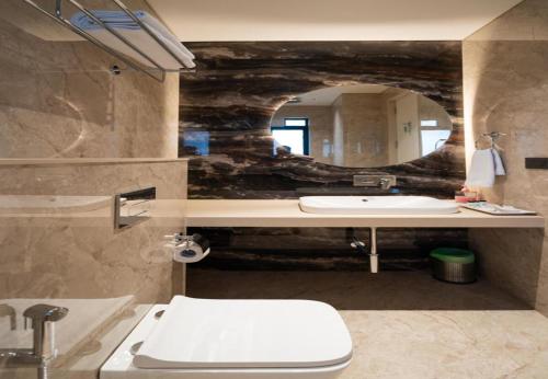 a bathroom with a sink and a toilet and a mirror at Airotel in Pune
