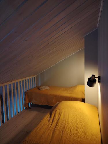 a bedroom with two beds and a wooden ceiling at Hotelli Hirsiranta in Ruokolahti