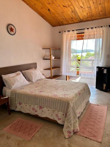 a bedroom with a bed and a large window at Pousada Tribo Do Sol in Ubatuba