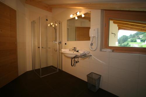 a bathroom with a sink and a shower with a mirror at Residence Rosengarten - Alpenglühen zum Anfassen, inklusive Guestpass in Tires