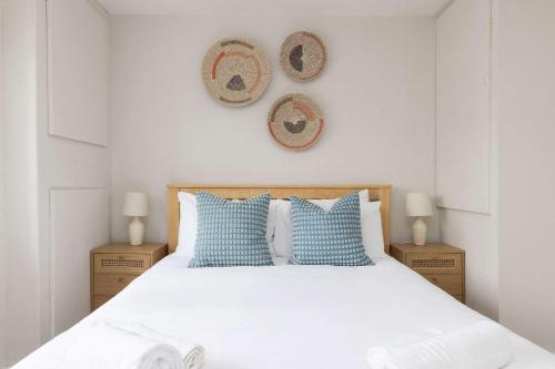a bedroom with a bed with blue and white pillows at Mariners: Stylish Beachside Getaway with Sea Views in East Wittering