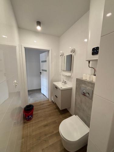 a white bathroom with a toilet and a sink at Nocleg Szwed-Pol in Jastrowie