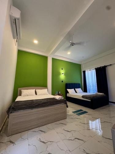 two beds in a room with a green wall at Muthugala Resort in Anuradhapura