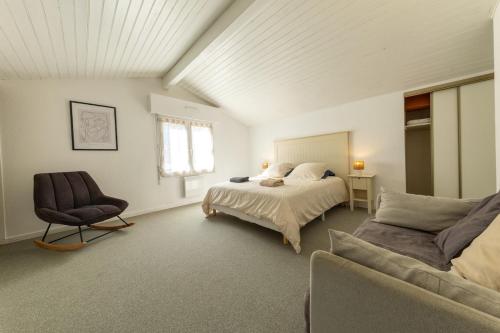 a bedroom with a bed and a chair and a couch at Les Mimosas in Ronce-les-Bains