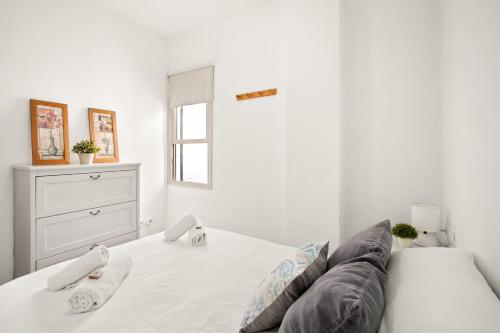 a white bedroom with a bed and a window at Apartamento Sa Mesquida 9 by 3VILLAS in Cala Llonga