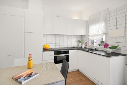 a kitchen with white cabinets and a table with a book at Apartamento Sa Mesquida 9 by 3VILLAS in Cala Llonga
