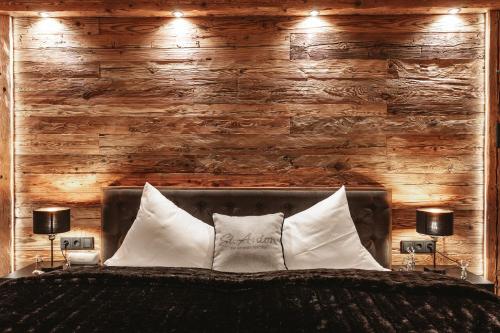 a bedroom with a wooden wall and a bed with pillows at StAnton Snow in Sankt Anton am Arlberg