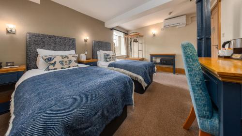 a bedroom with two beds with blue comforters and a desk at Ennios Boutique Hotel in Southampton